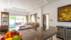 A modern kitchen with a granite countertop, a built-in oven, and a large window overlooking a pool. - Private 3 Bedroom Pool Villa PP10 (Hua Hin)