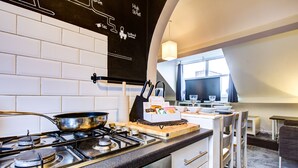 A modern kitchen with a gas stove, white cabinets, and a chalkboard wall with writing. - Entire Artistic Open-plan Top Floor Apartment (Westcliff-on-Sea)