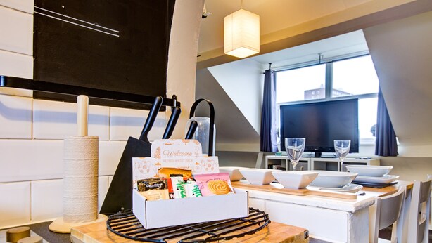 A kitchen with a countertop holding a welcome pack, a cat tree, and a cutting board. - Entire Artistic Open-plan Top Floor Apartment (Westcliff-on-Sea)