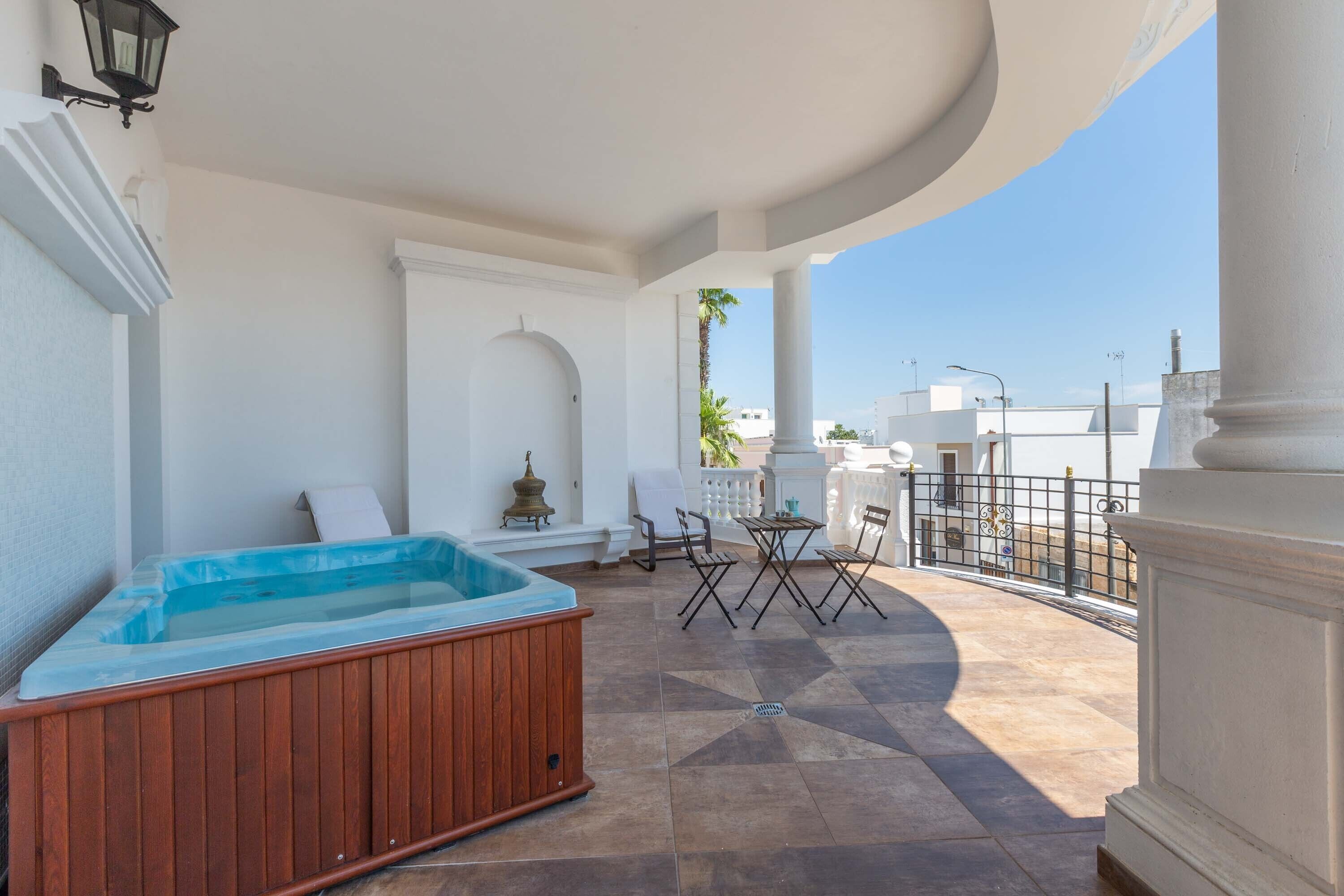 A covered outdoor area with a hot tub, seating, and a view of the cityscape.