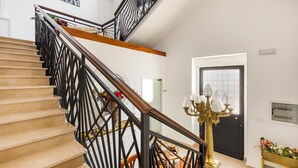A staircase with black railings and a wooden handrail, leading to a landing with a chandelier and a door. - 2448 Palazzo Montagna - Suite by Barbarhouse (Melissano)
