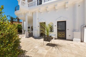 A white building with a balcony, a door with a metal gate, and a potted plant. - 2448 Palazzo Montagna - Suite by Barbarhouse (Melissano)