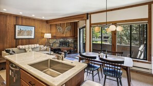 A modern kitchen with a large island, wooden accents, and a stone fireplace. - One Bedroom walking distance to Palisades Tahoe! (Olympic Valley)