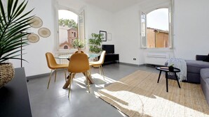 Moderni olohuone, jossa on ruokailutila, suuret ikkunat ja näkymä ulkona olevaan rakennukseen.