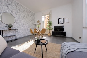 Un salon moderne comprenant un canapé, une table à manger avec des chaises, un téléviseur et une grande fenêtre.