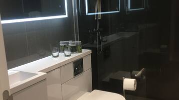Un baño moderno con inodoro, lavabo y cabina de ducha de vidrio.