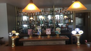 A bar area with multiple liquor bottles, a selection of taps, and overhead lighting.