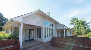 Una casa de dos pisos con un porche cubierto, ventanas amplias y una terraza de madera.