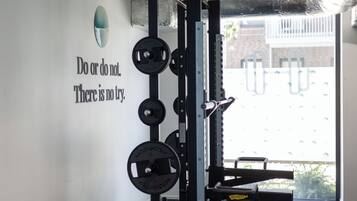 Een sportschool met gewichthefapparatuur en een motiverende quote op de muur.