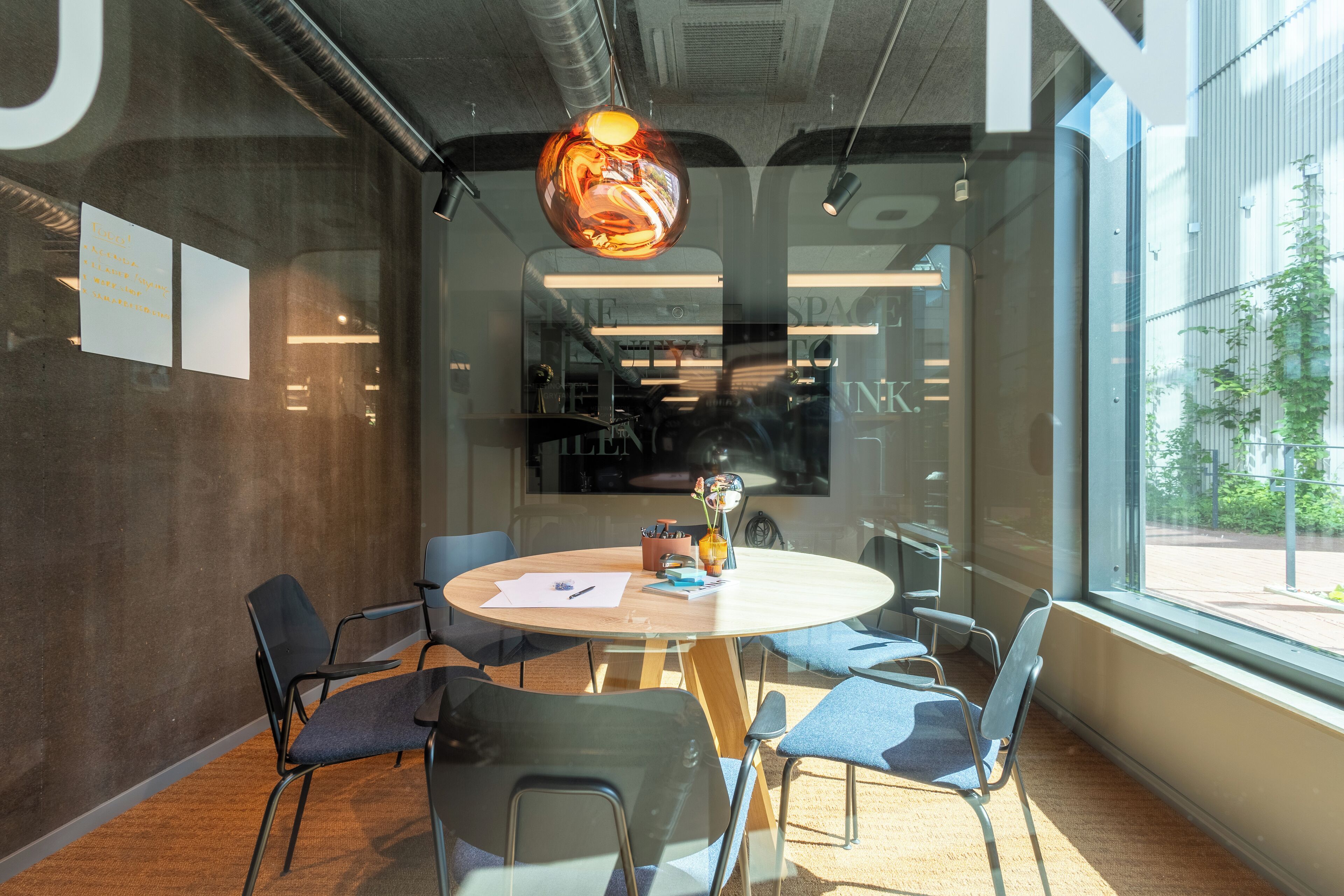 A conference room with a round table, chairs, and a large window.