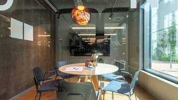 A conference room with a round table, chairs, and a large window.