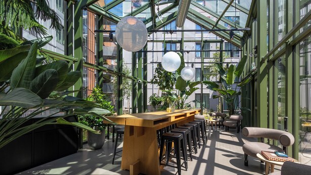 A modern indoor space with a long wooden bar, multiple stools, and comfortable seating areas. - Unity Malmö - A Studio Hotel (Malmö)