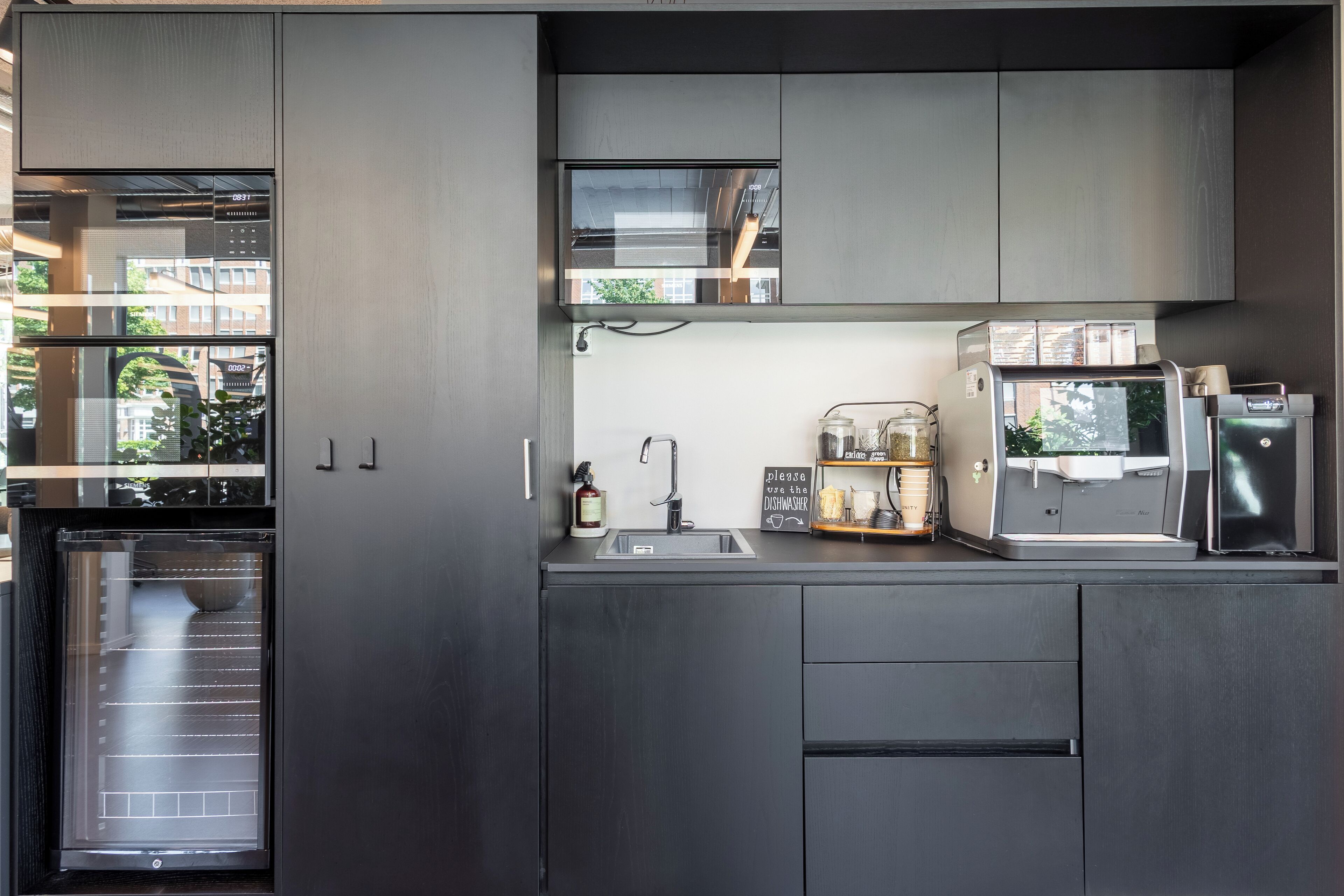 A modern kitchen with a built-in oven, a sink, and a coffee machine.