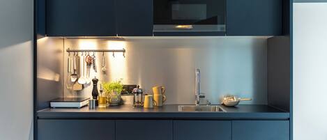 A modern kitchen with dark cabinetry, a stainless steel sink, and a built-in oven.