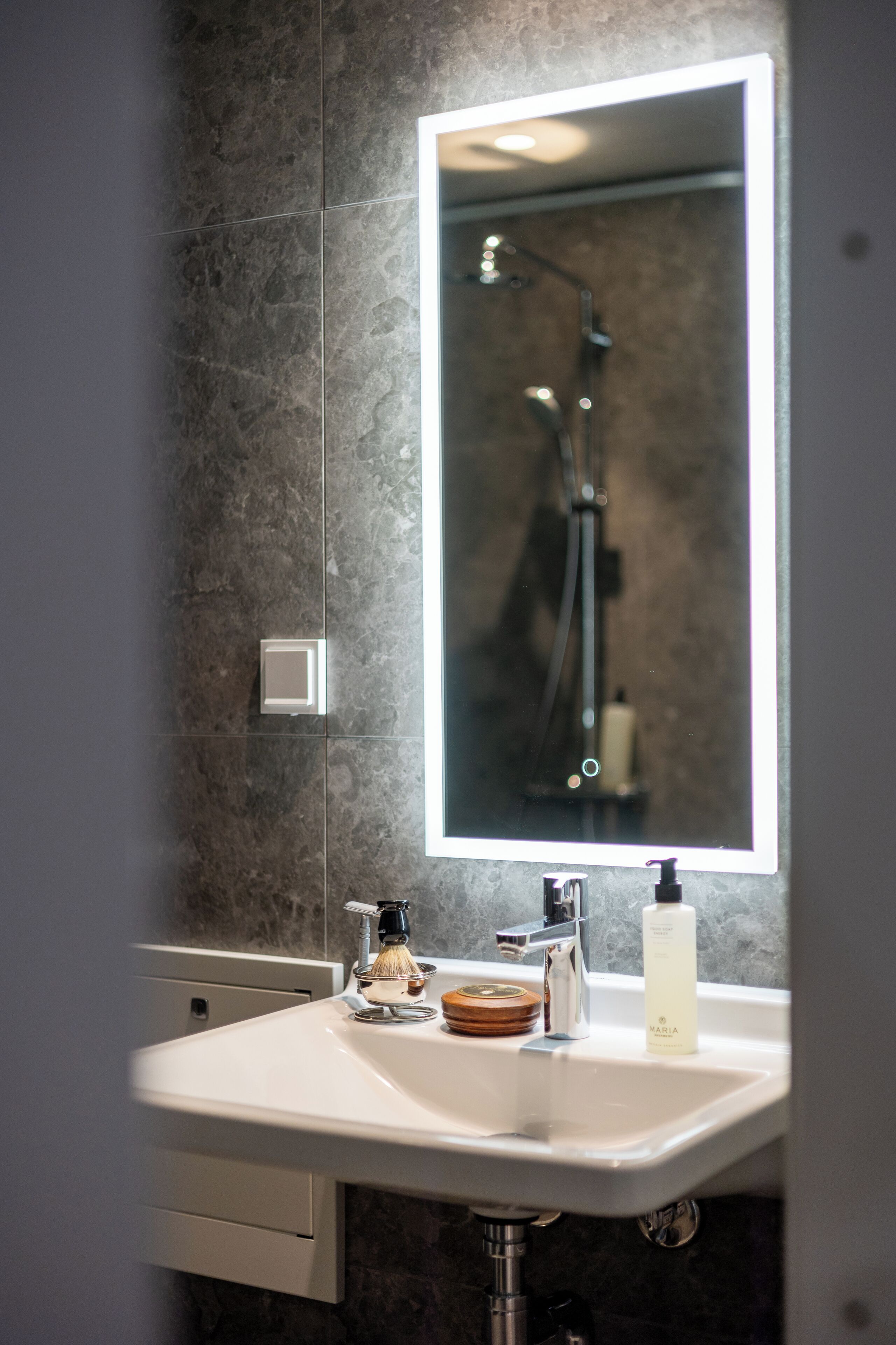 A bathroom with a white sink, a mirror, and a shower.