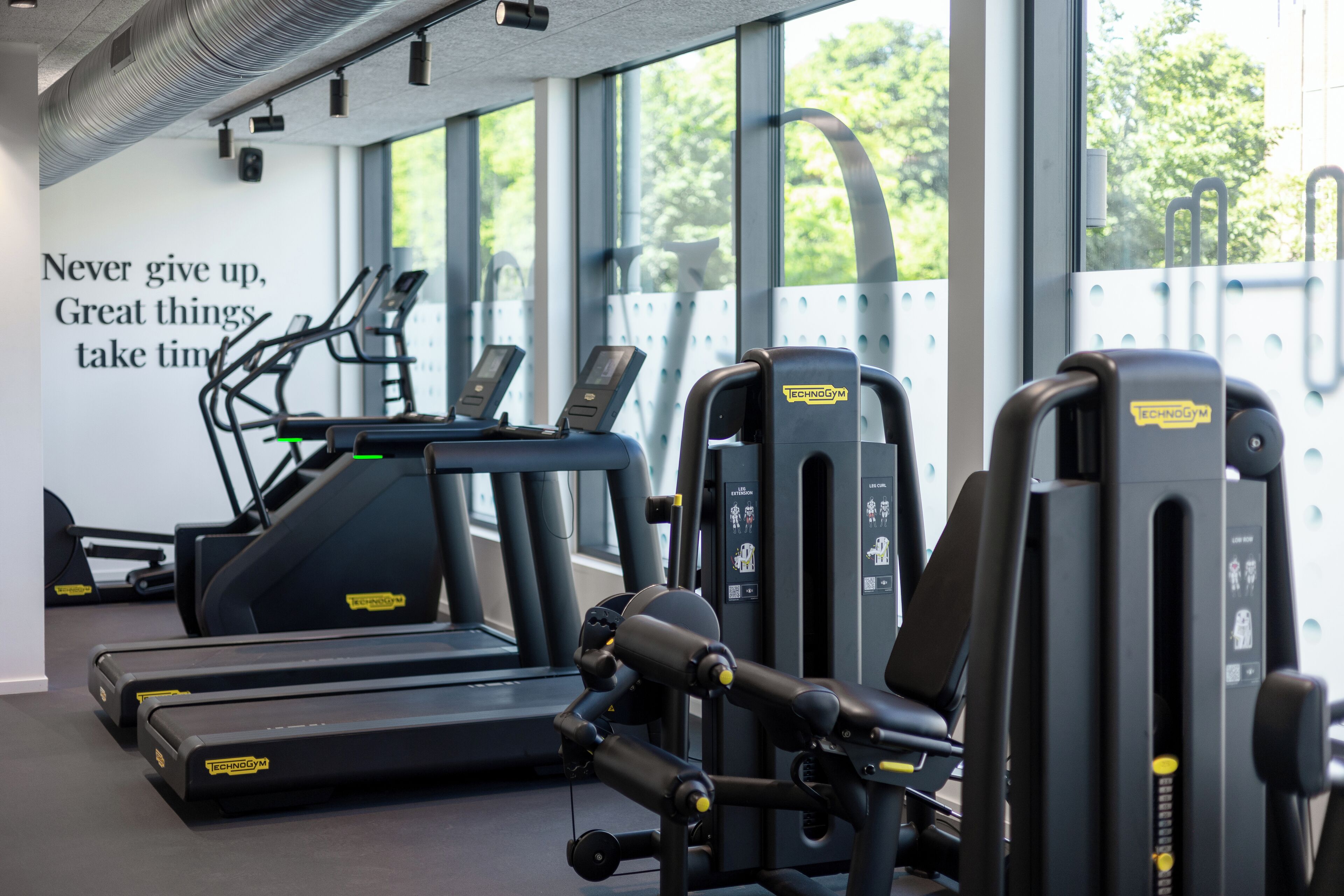 A gym with treadmills, weight machines, and a motivational quote on the wall.