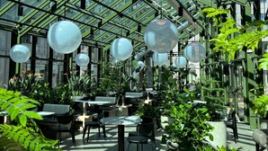 A greenhouse-style interior with glass ceilings, tables, chairs, and potted plants. - Unity Malmö - A Studio Hotel (Malmö)