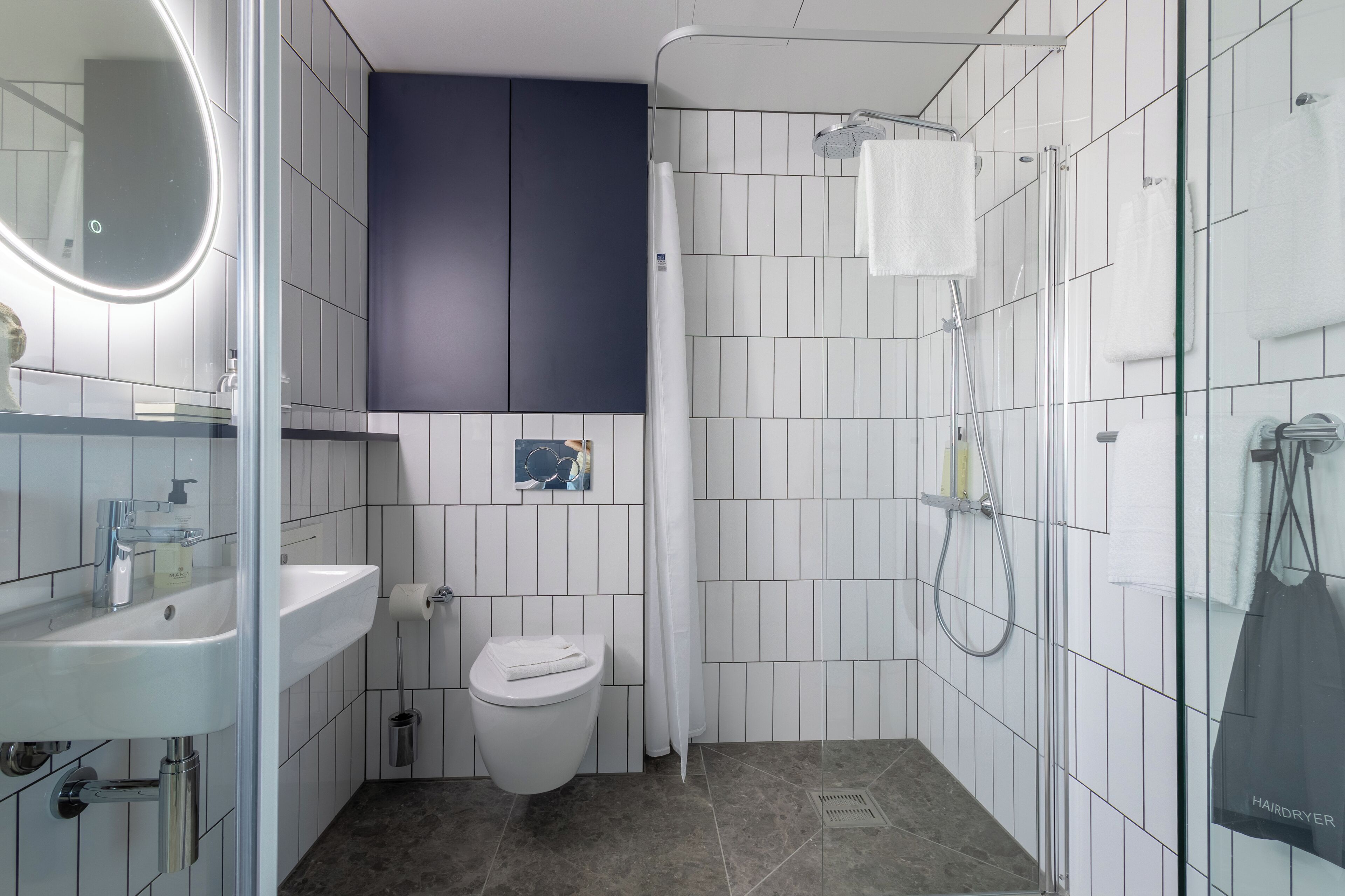 Un baño moderno con lavamanos, inodoro y ducha blancos.
