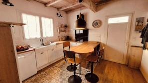 Una cocina compacta con armarios blancos, una mesa de comedor de madera y un piso con diseño.