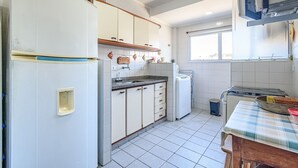 A kitchen with white cabinets, a granite countertop, a stove, and a window. - Raridade - Apt próx praia vista mar ar con (Ubatuba)