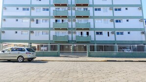 A multi-story residential building with a tiled facade, balconies, and a gated entrance. - Raridade - Apt próx praia vista mar ar con (Ubatuba)