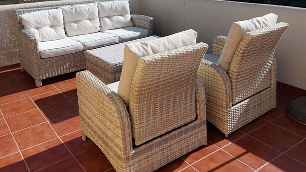 Een terras met rieten meubilair en uitzicht op zee.