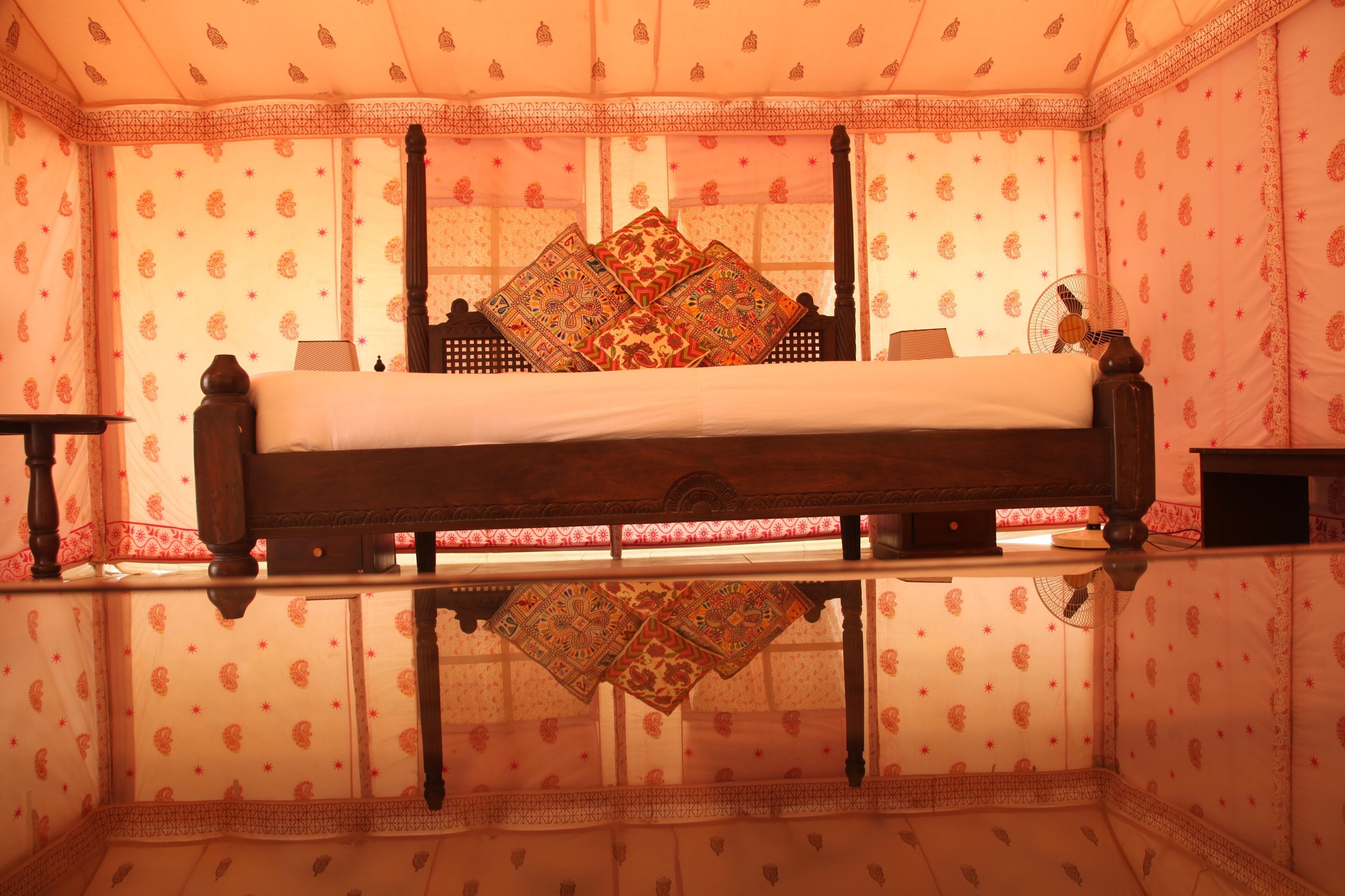 Une chambre avec un lit, un miroir et un papier peint à motifs.