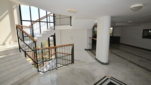 A multi-level interior with marble flooring, a staircase with black railings, and white walls. - Sun Hill Los Pacos 2 Bed Apt (Fuengirola)