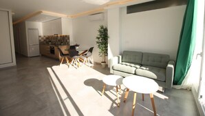 A modern living room with a grey sofa, two round tables, and a dining area with chairs. - Walking Distance to beach Torreblanca Rio Sol (Fuengirola)