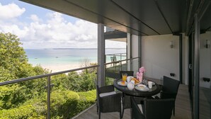 A balcony with a table set for breakfast, overlooking a beach and ocean. - Waters Edge (St Ives)