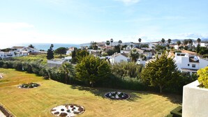 A coastal residential area with white houses, green lawns, and palm trees. - Seaviews Balcones de Chaparral 3 Bed Apt (Mijas Costa)