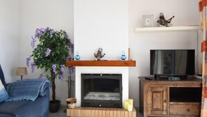 A living room with a fireplace, a sofa, a television, and a potted plant. - Seaviews Balcones de Chaparral 3 Bed Apt (Mijas Costa)