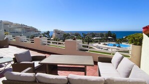 A rooftop terrace with outdoor furniture, a pool, and a view of the sea. - Seaviews Balcones de Chaparral 3 Bed Apt (Mijas Costa)