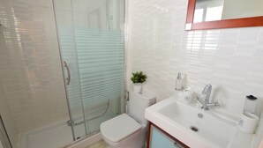 A bathroom with a glass-enclosed shower, a toilet, and a sink with a mirror above it. - Mirador De Mijas  Penthouse Apt Blq 2 (Mijas Pueblo)