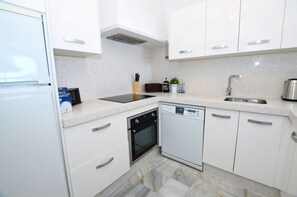 Eine moderne Küche mit weißen Schränken, einem eingebauten Backofen, einem Geschirrspüler und einer Arbeitsplatte aus Granit.