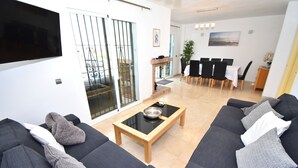 A modern living room with two sofas, a coffee table, and a dining area with chairs and a table. - Wyndham Resort 4 Bed House (Mijas Costa)