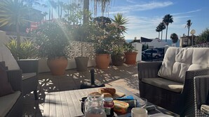 A patio with wicker furniture, potted plants, and a table set with food and drinks. - Wyndham Resort 4 Bed House (Mijas Costa)