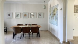 Un coin repas avec une table en bois et quatre chaises, des œuvres d’art encadrées au mur et une grande carte du monde.