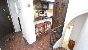 Eine Küche mit Mikrowelle, Barhocker und einer Treppe mit Geländer.