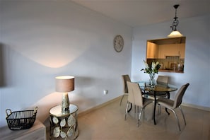 Un coin repas avec une table ronde, des chaises, une lampe et une horloge au mur.