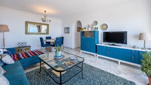 Ein Wohnzimmer mit einer Couch, einem Couchtisch, einem Fernseher und blauen Schränken.