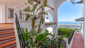 Eine Treppe mit Geländer, Blick auf das Meer und ein Balkon mit Pflanzen.