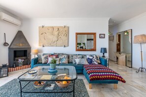 A living room with a sofa, coffee table, fireplace, and a large mirror. - Stunning Views Mirador de Mijas Apt (Mijas Pueblo)