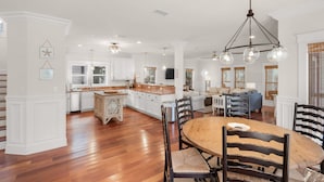 A spacious kitchen with white cabinetry, a wooden island, and a dining area with a round table and chairs. - Seacrest Beach Home for 19, Huge Pool & Beach Tram + Free Attraction Tickets! (Seacrest Beach)