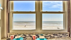 A kitchen with a view of the beach through a window, a countertop with a placemat, and two bowls on it. - Oceanfront Daytona Beach Condo w/ New Pool! (Daytona Beach)
