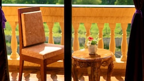 Un balcón con una silla de madera y una mesa pequeña con un florero.
