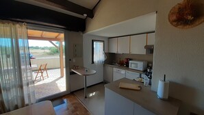 Cozinha compacta com micro-ondas, pia e um pequeno espaço de refeições com mesa e cadeiras.
