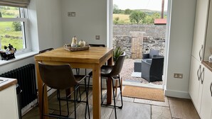 A kitchen with a wooden table, chairs, and a view of the outdoors. - Penderyn Cottage, Waterfall Country, Brecon Beacons (Aberdare)