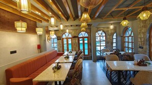 A restaurant with wooden beams, stone walls, and arched windows. Tables and benches are arranged for dining. - HOTEL ALPINE MUSK (Tehri)