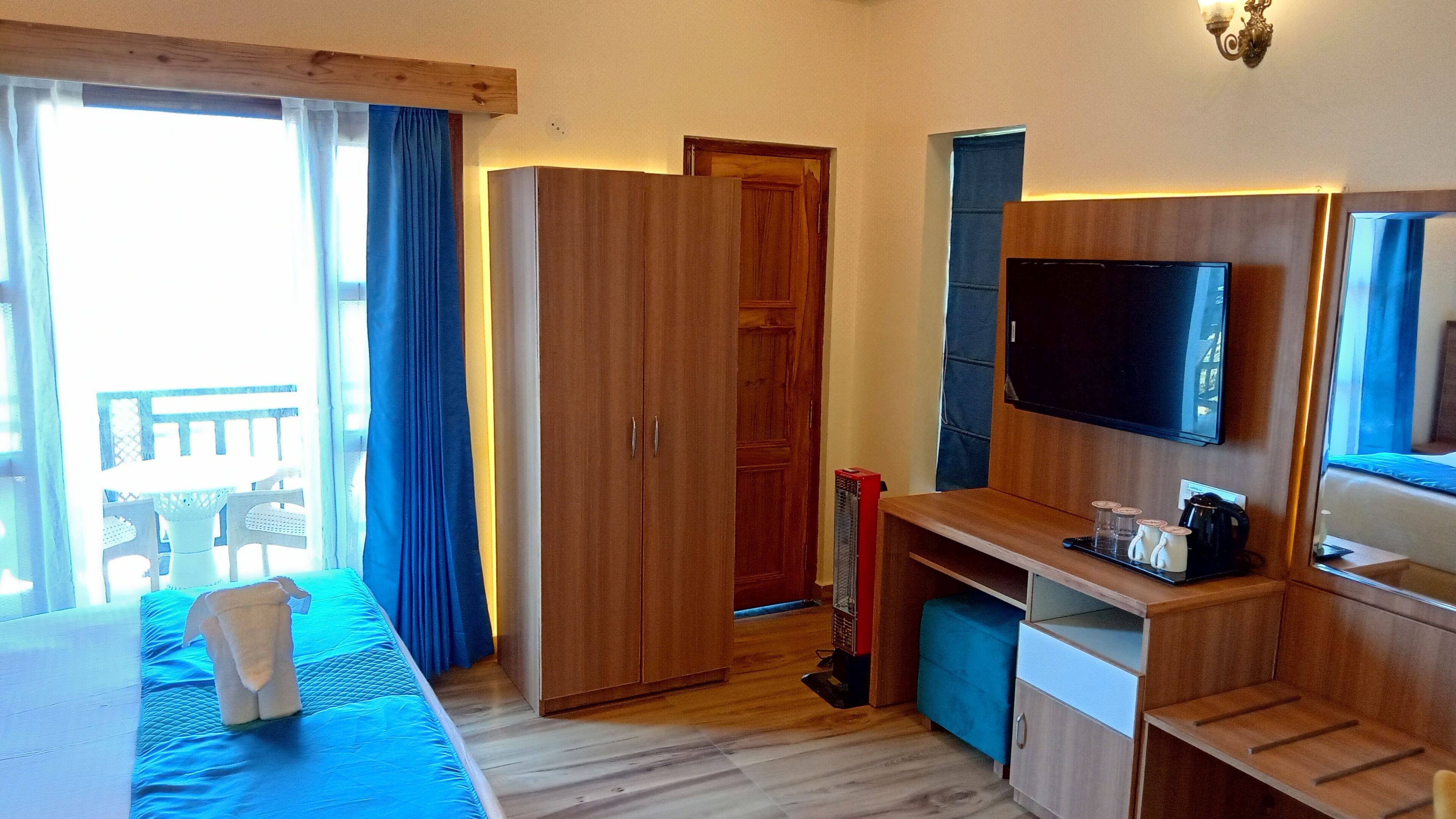 A hotel room with a bed, a desk, a television, and a wardrobe.